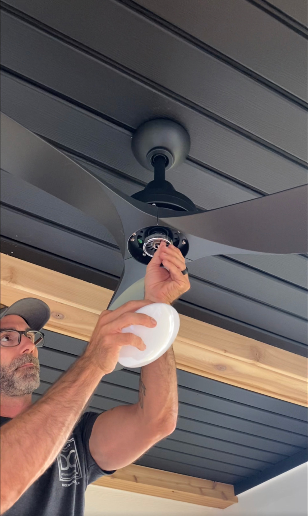 A man adjusting the wires on a ceiling fan. A man adjusting the wires on a ceiling fan.
