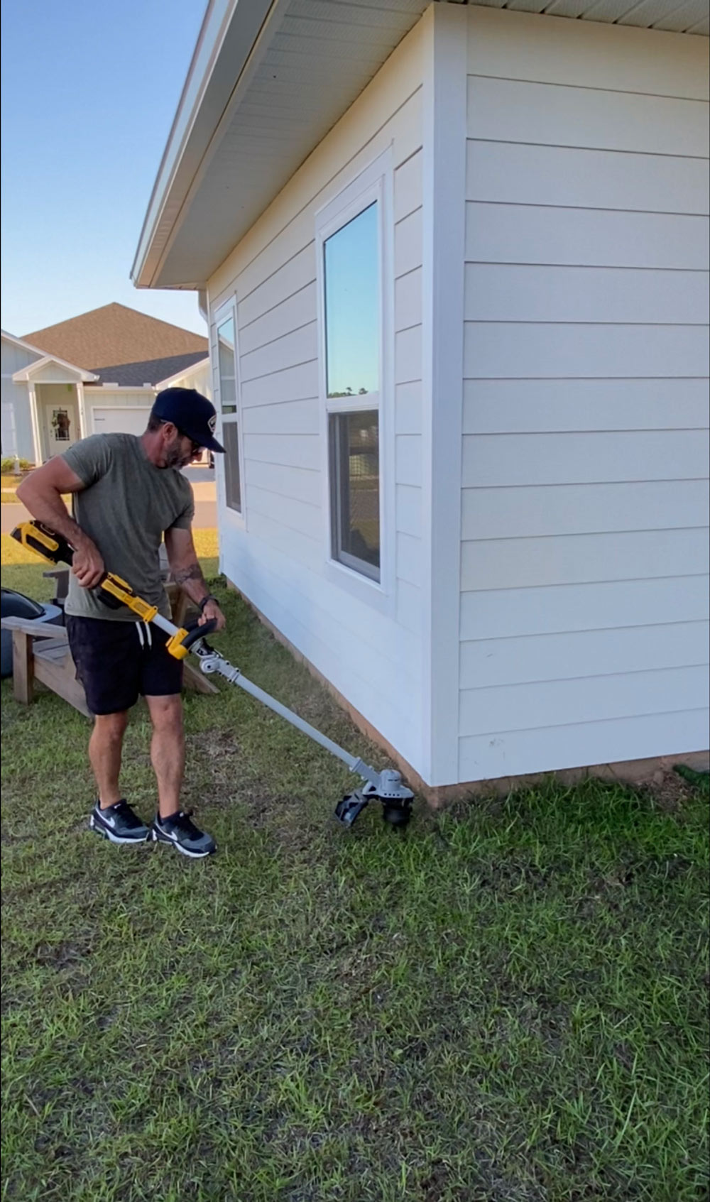 A man edging the lawn with a DeWalt trimmer. A man edging the lawn with a DeWalt trimmer.