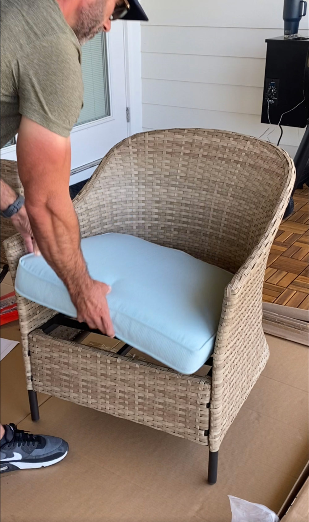 A man adding cushions to a wicker patio chair. A man adding cushions to a wicker patio chair.