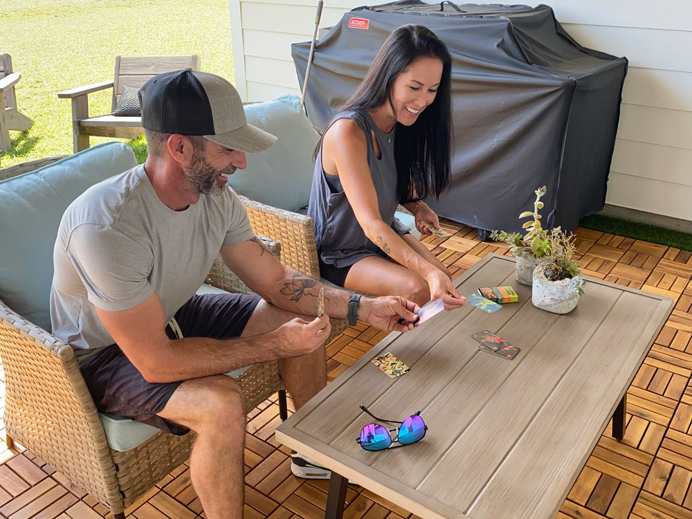 A man and woman playing a card game in a backyard patio seating area. A man and woman playing a card game in a backyard patio seating area.