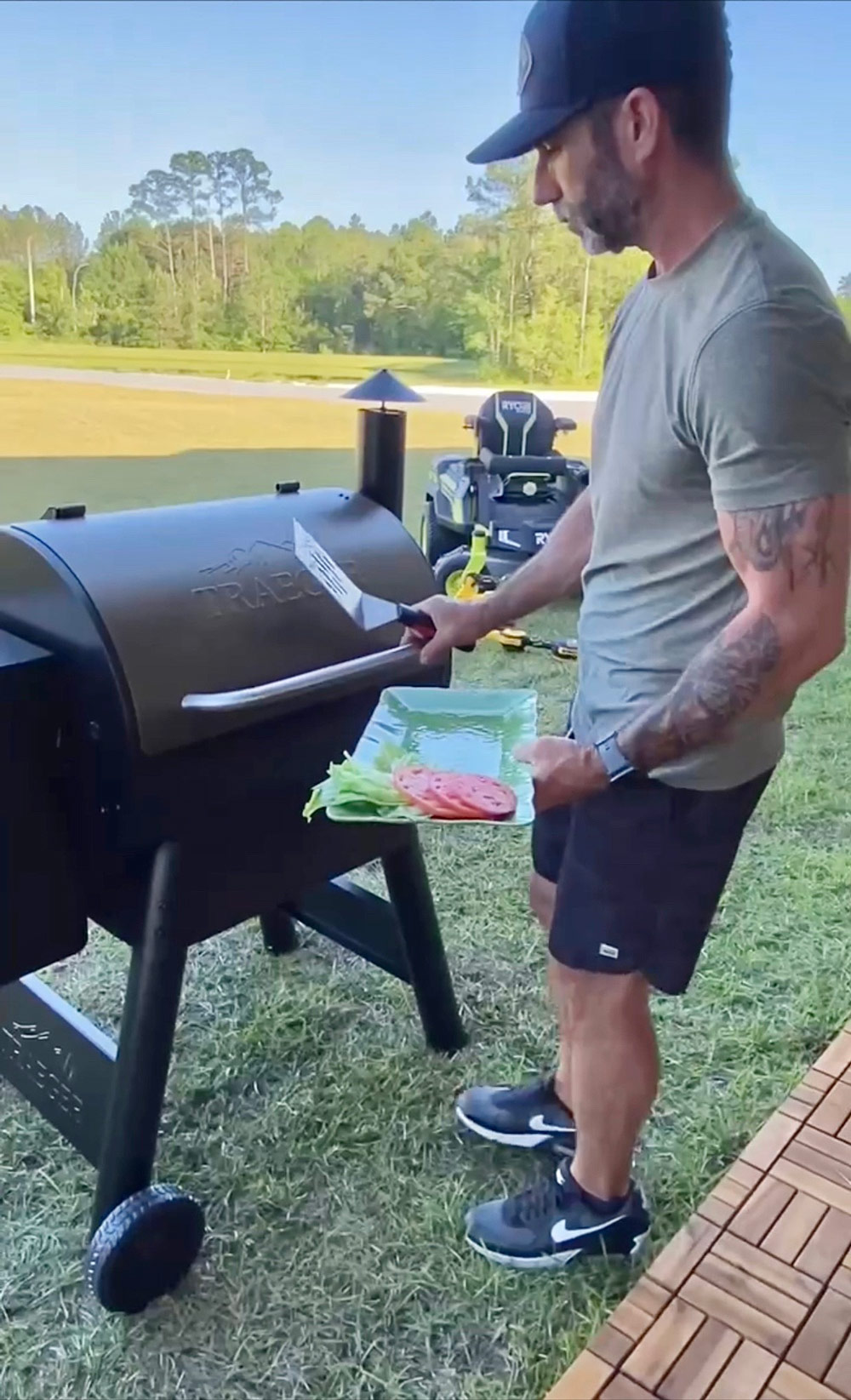 A man holding a plate with burger toppings, removing food from a grill. A man holding a plate with burger toppings, removing food from a grill.