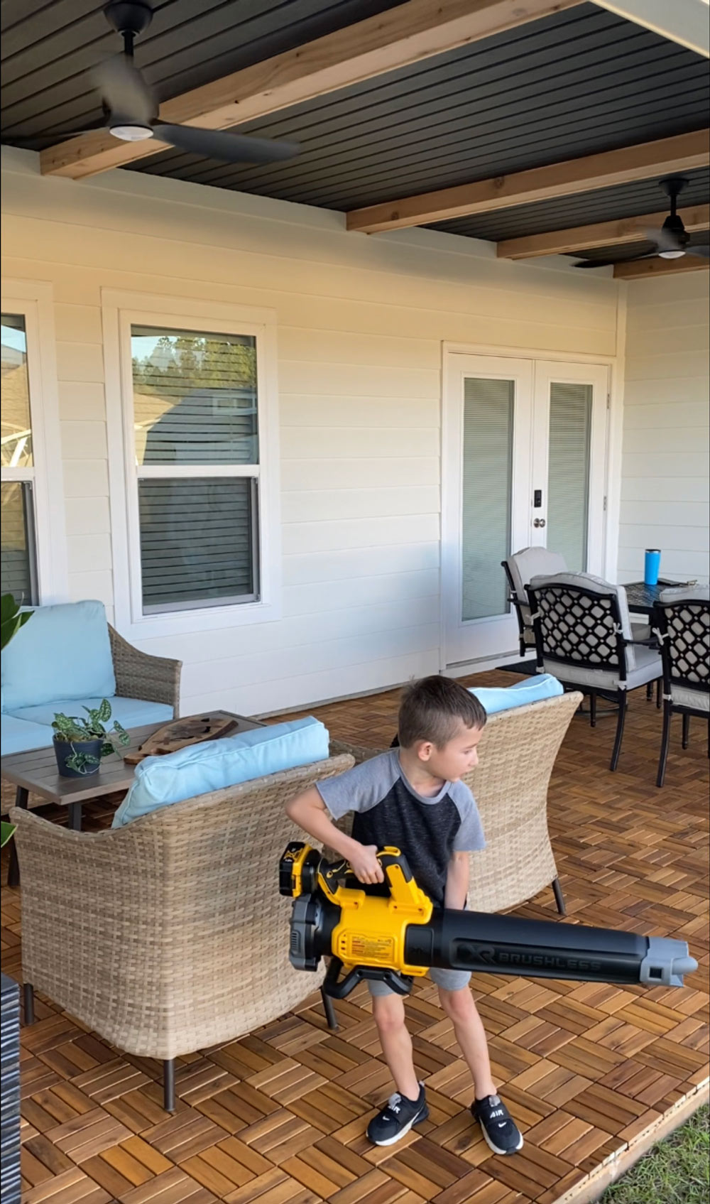 A little boy standing on a patio holding a leaf blower. A little boy standing on a patio holding a leaf blower.