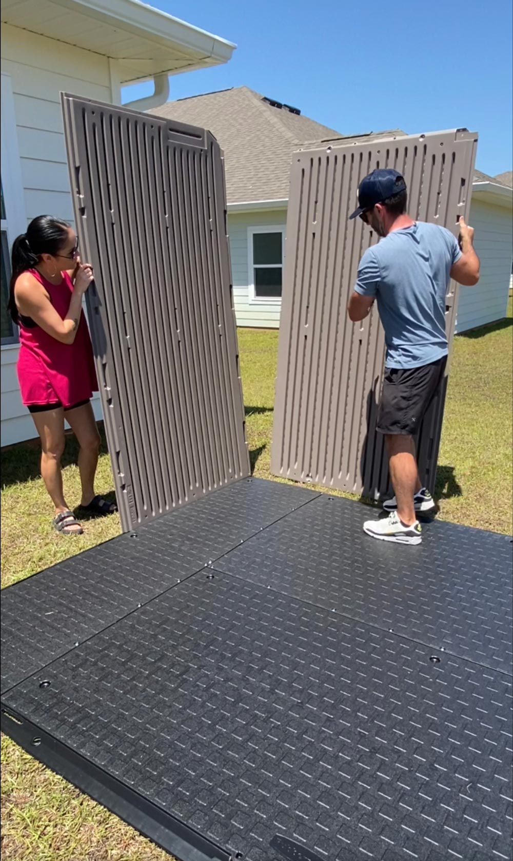 A man and woman assembling the sides of an outdoor shed. A man and woman assembling the sides of an outdoor shed.