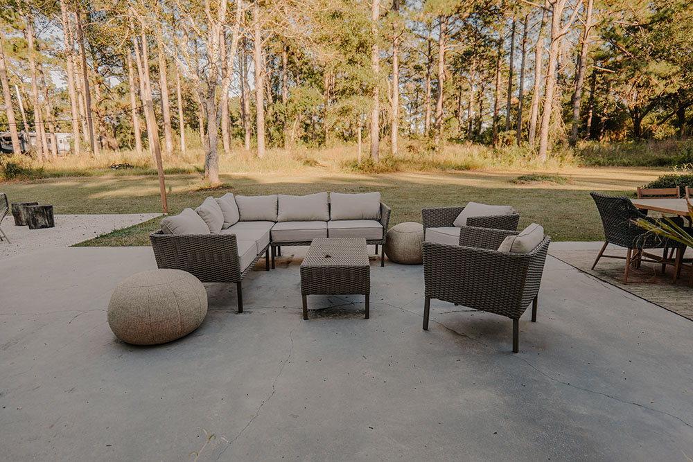 A plain outdoor patio with a few pieces of furniture scattered around. A plain outdoor patio with a few pieces of furniture scattered around.