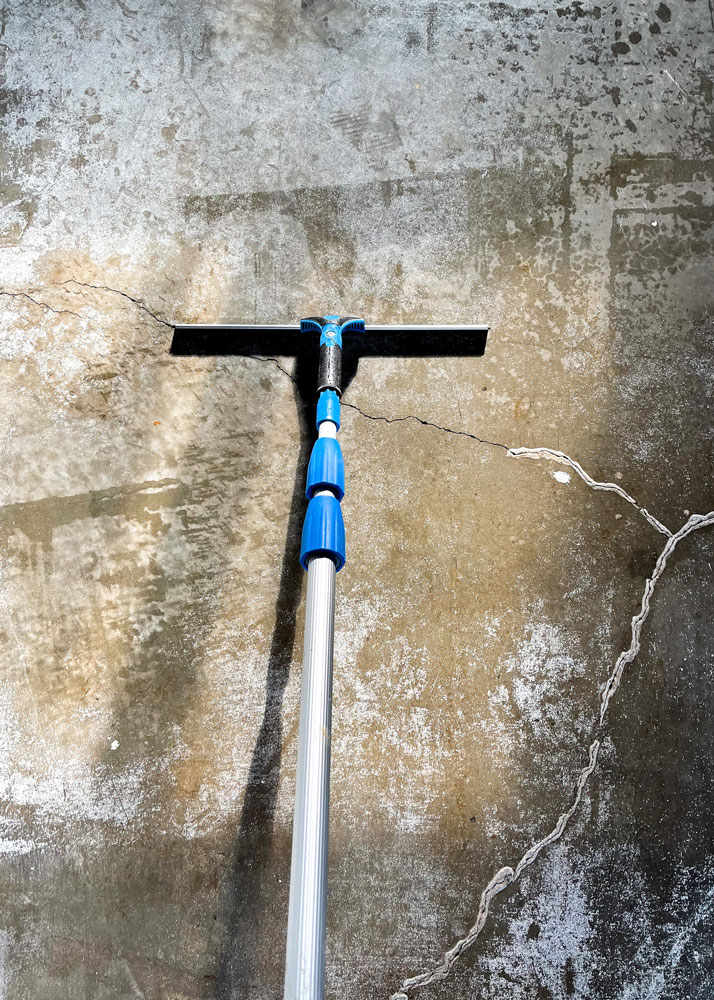 Squeegee on a silver pole on the garage floor. Squeegee on a silver pole on the garage floor.