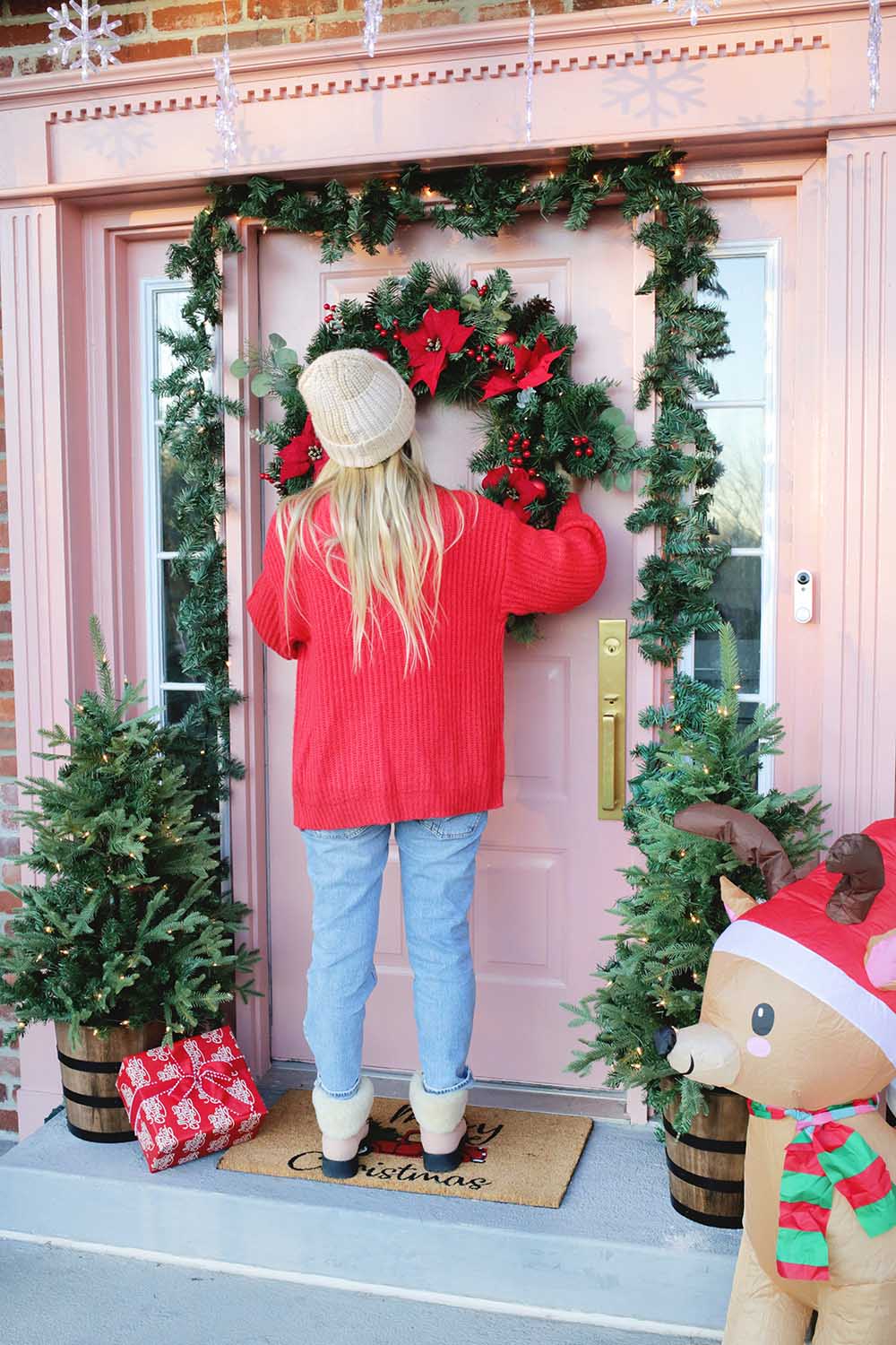 A woman placing a wreath on her front door.