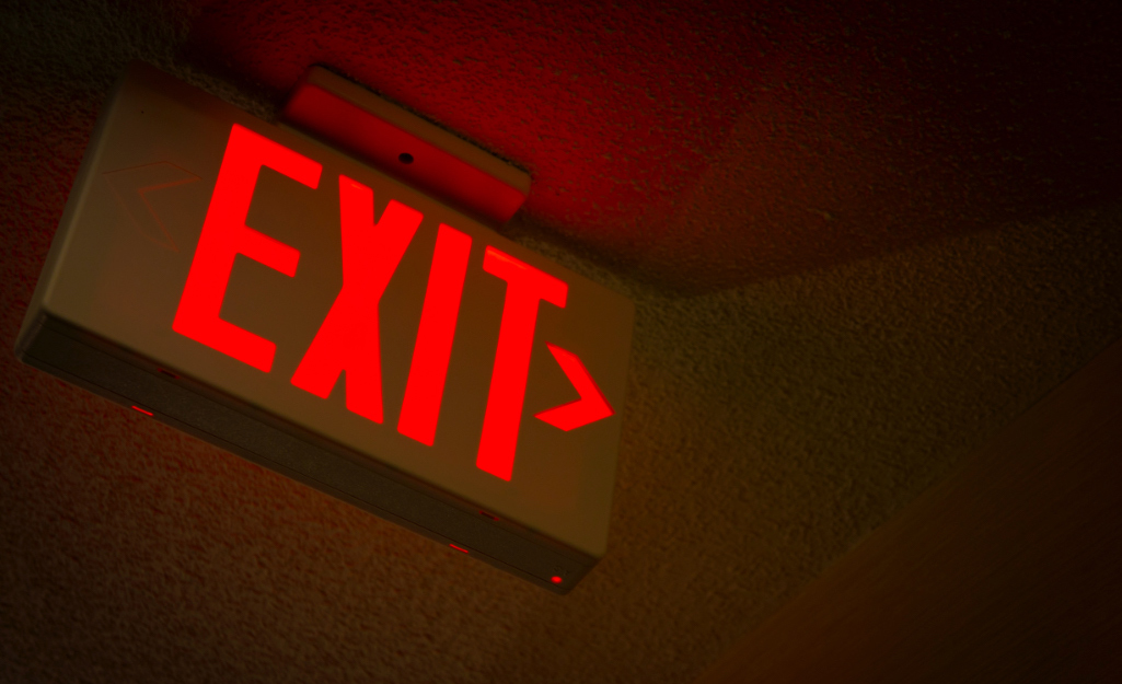An emergency exit sign illuminates a darkened hallway. An emergency exit sign illuminates a darkened hallway.