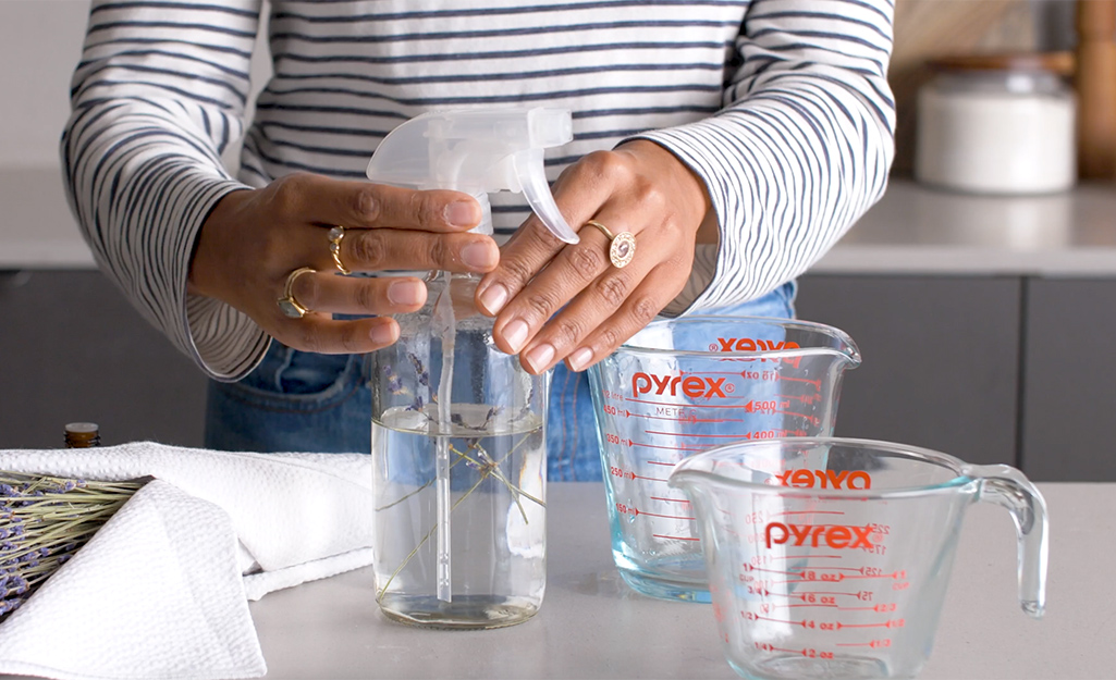 A woman fills a spray bottle with vinegar for cleaning.