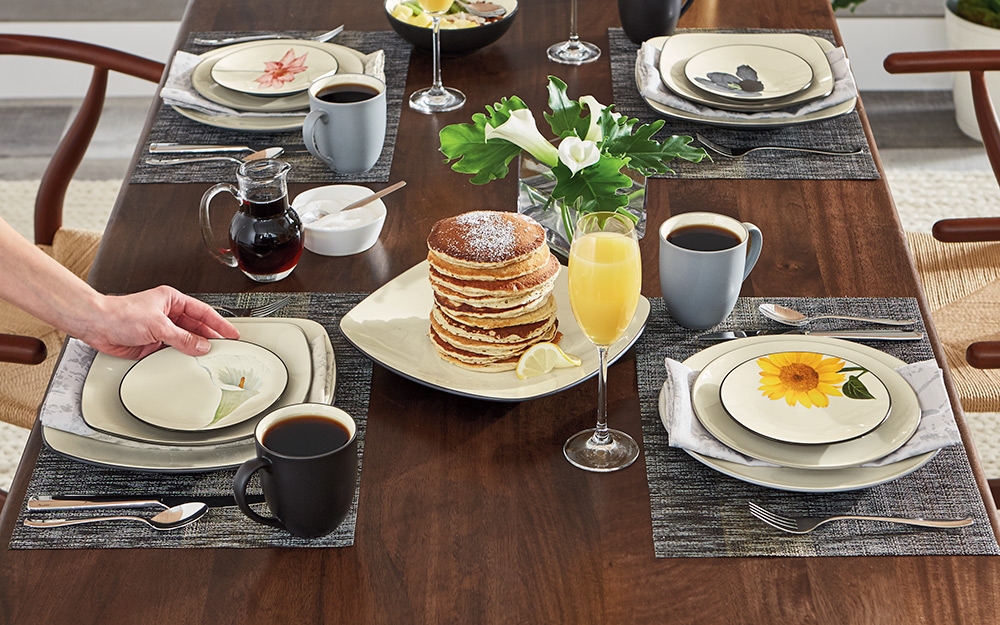 Four casual place settings at a breakfast table with pancakes.
