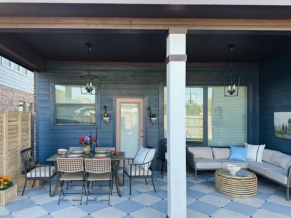A patio with checkered floors, an outdoor table and a couch. A patio with checkered floors, an outdoor table and a couch.