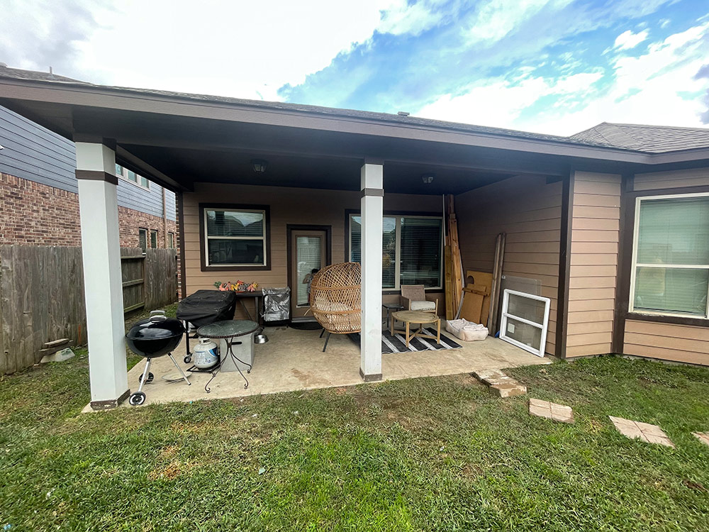 Front view of a yard and back patio full of chairs, wood and grills. Front view of a yard and back patio full of chairs, wood and grills.