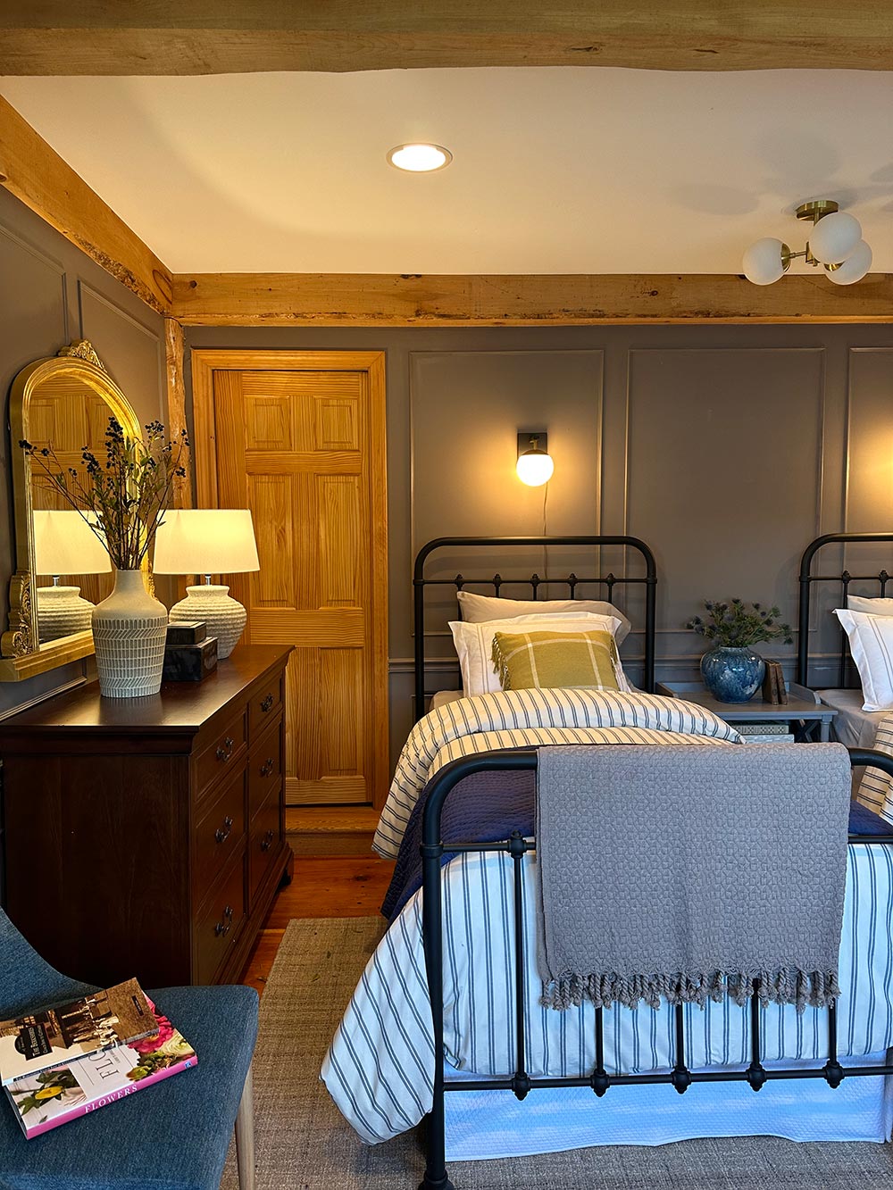 A twin bed with striped sheets and a dark wood dresser. A twin bed with striped sheets and a dark wood dresser.