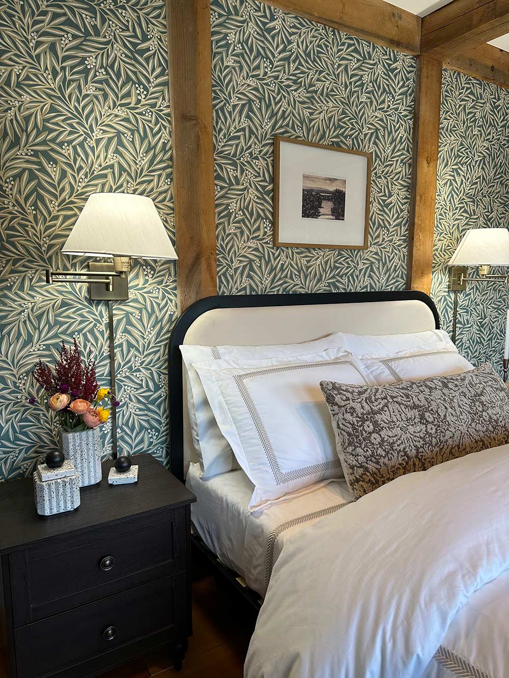 Full white bed with green and white wallpaper and sconces. Full white bed with green and white wallpaper and sconces.