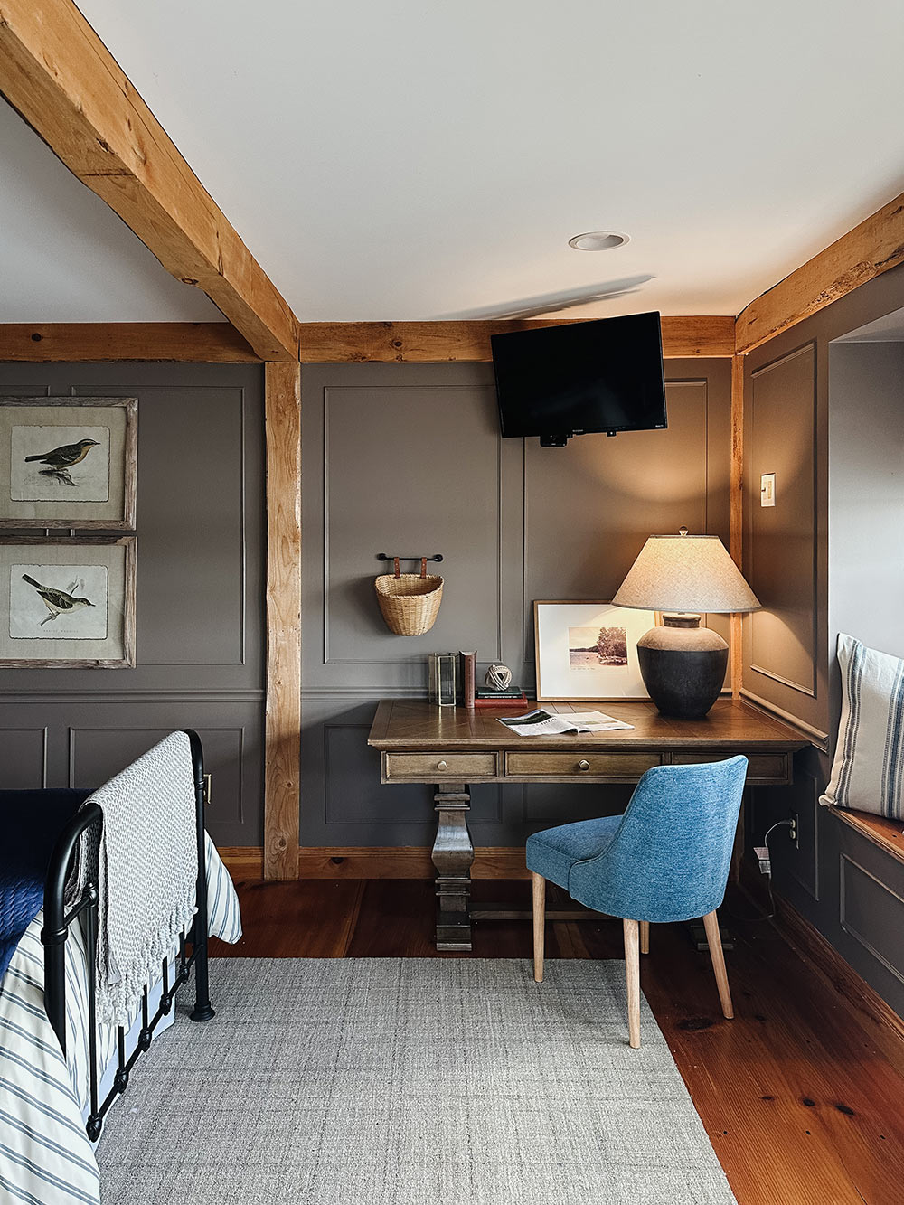 A wooden desk with a cloth blue chair in the corner of a bedroom. A wooden desk with a cloth blue chair in the corner of a bedroom.
