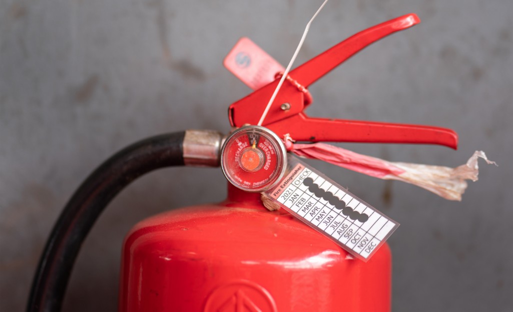 A fire extinguisher with a label indicating 9 completed inspections this year.