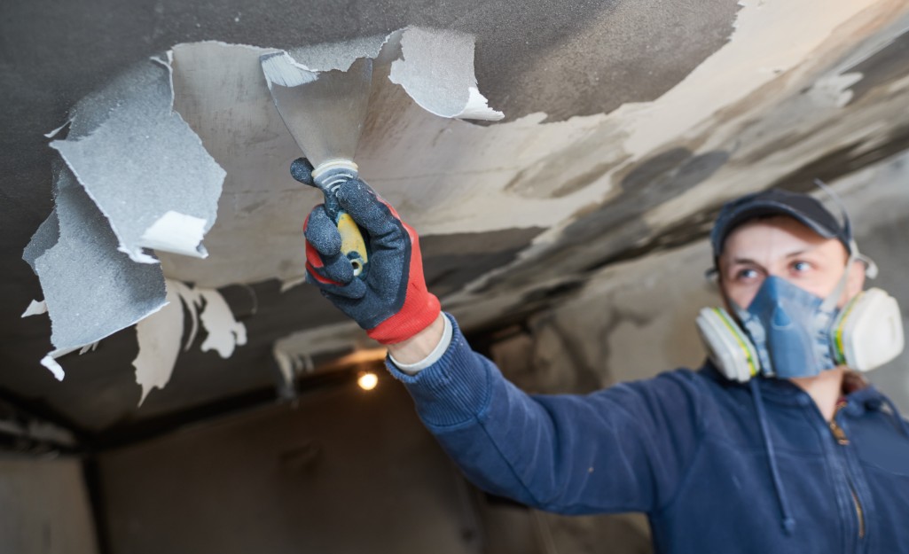 A restoration Pro removes paint from a ceiling after a fire.