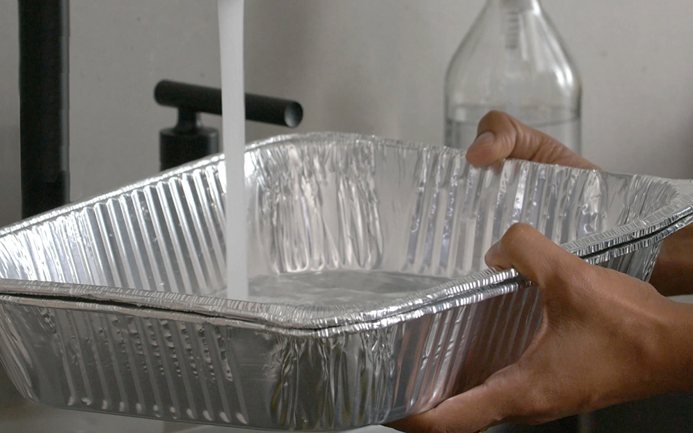 A person filling a pan with water. A person filling a pan with water.