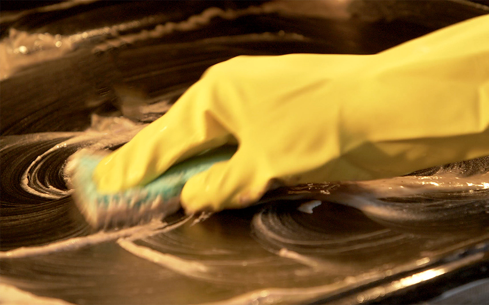 A person scrubbing a treated surface in the oven. A person scrubbing a treated surface in the oven.