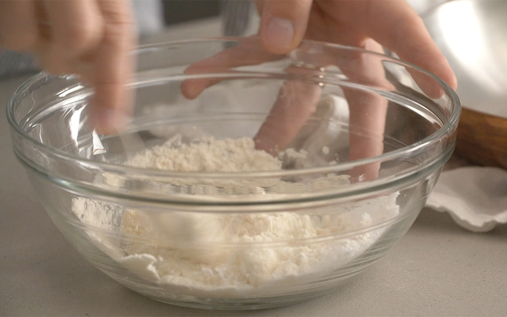 A person mixes flour and vinegar to polish copper.