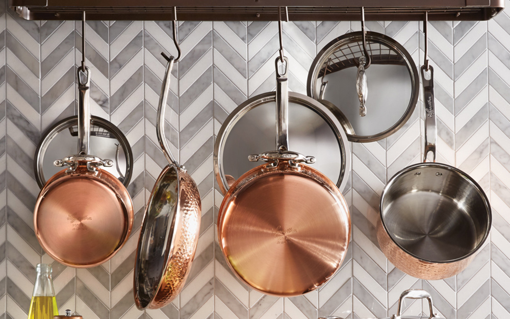 Shiny copper cookware hangs on display.