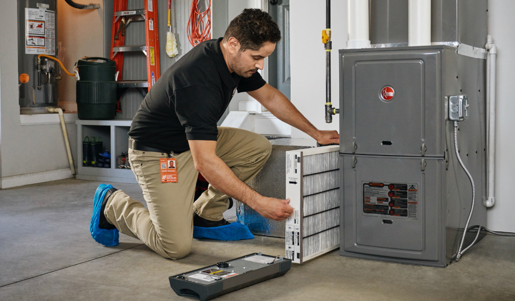 An HVAC technician replaces an air filter.