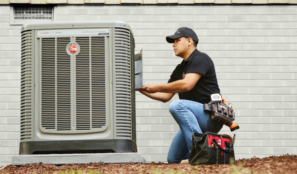 An HVAC technician checks a condenser.