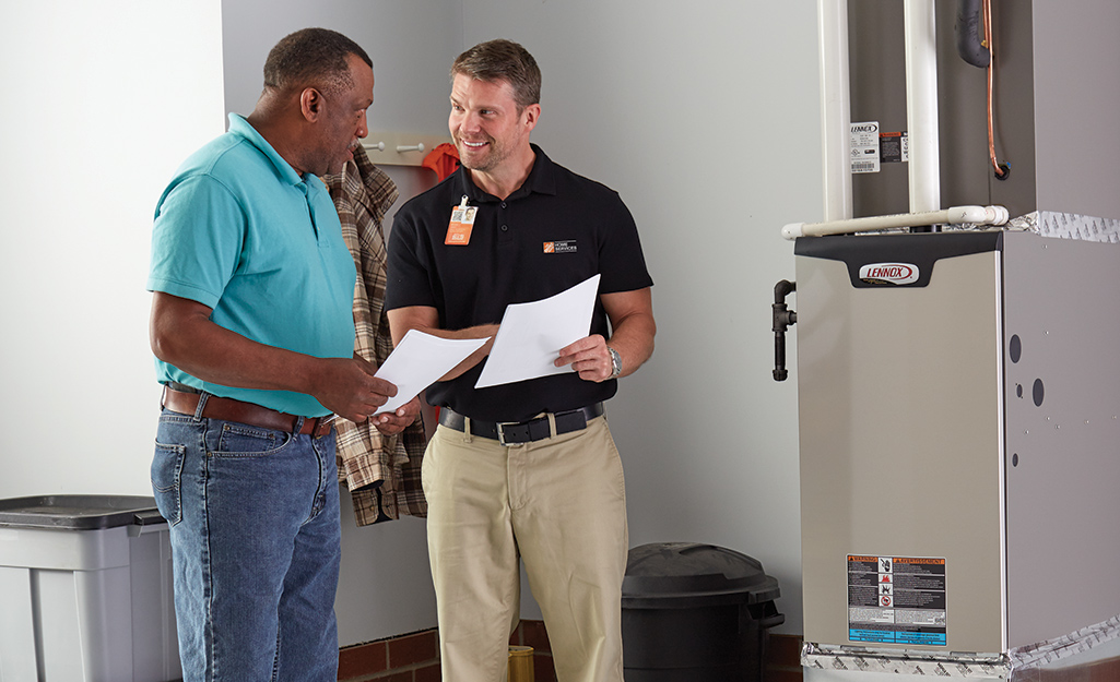 A homeowner talking to a Home Depot associate next to a furnace.