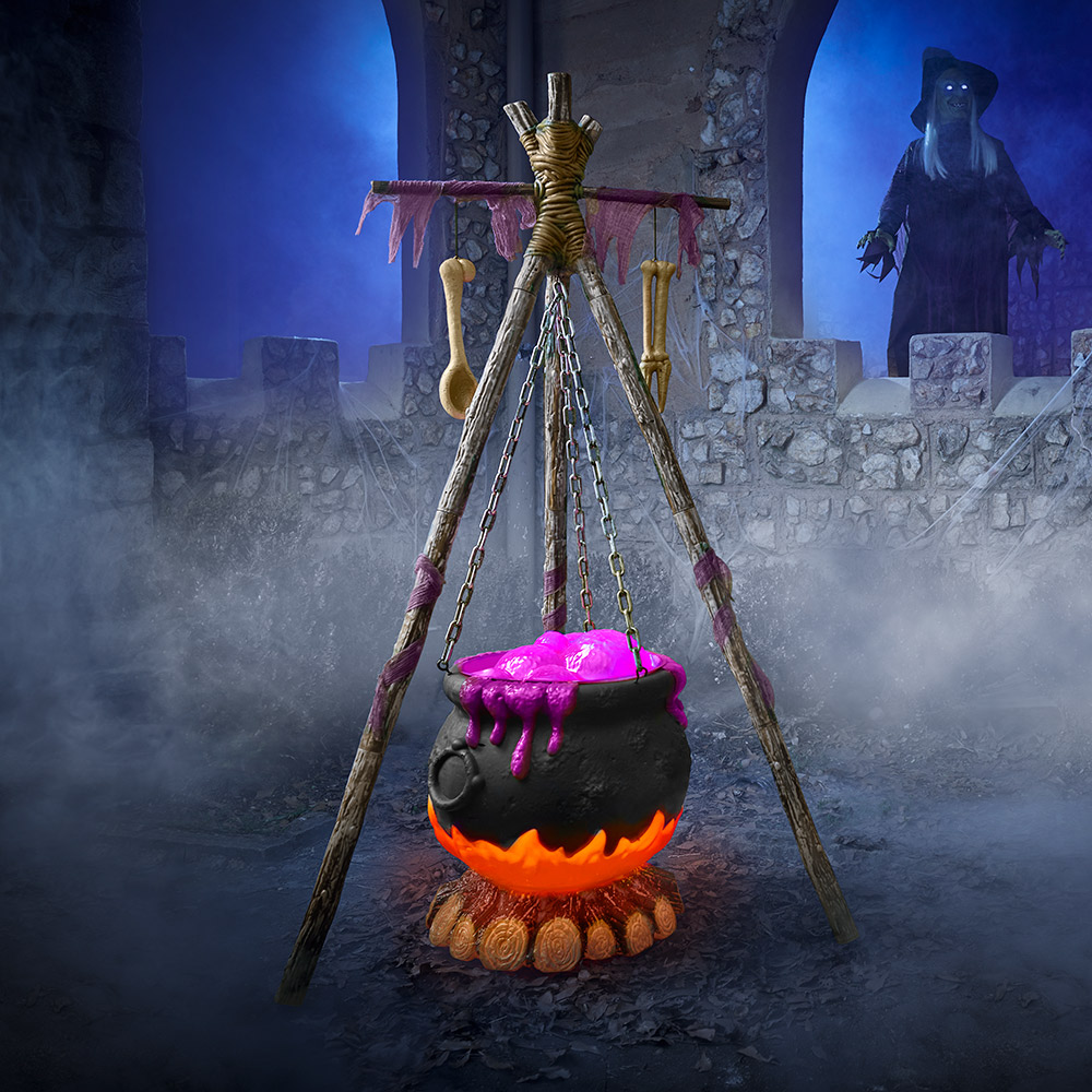 A spooky cauldron with a witch on top of a castle wall in the background.
