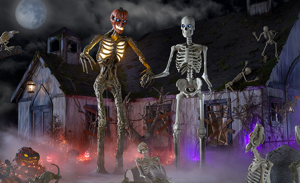 The Inferno skeleton mannequin and 12-foot skeleton in front of a Halloween-themed house.