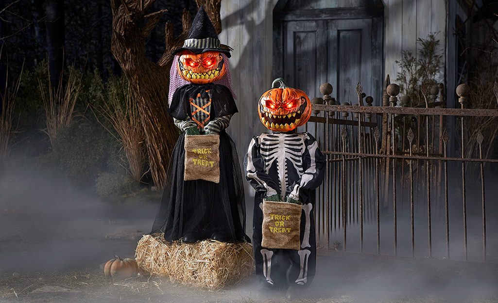 A pair of life-sized trick-or-treat figures with jack o' lantern heads.