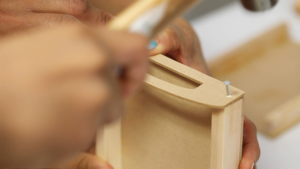 Handles are secured to the side of the tray with nails.