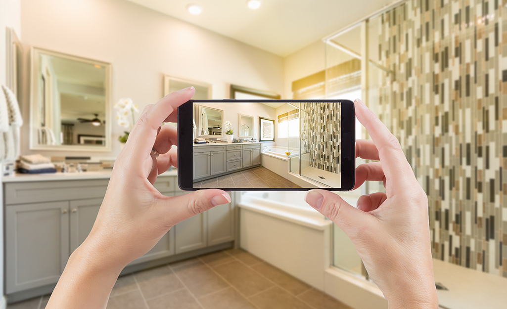 A person takes a picture of a bathroom with a smartphone.