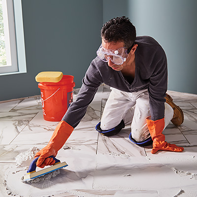 A person using a grout float to apply grout to tile.