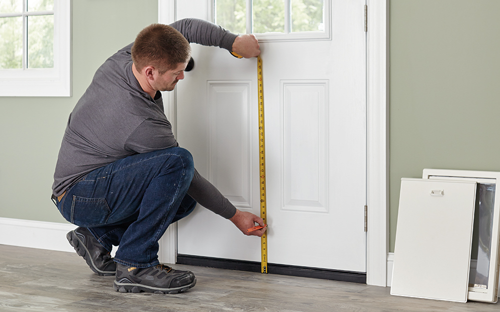 A man measuring the bottom of an exterior door