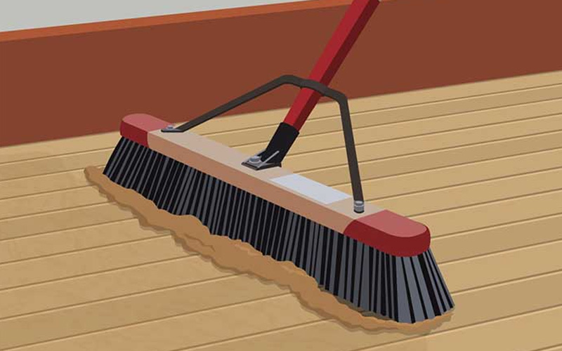An illustration shows dust on a hardwood floor being swept by a broom. An illustration shows dust on a hardwood floor being swept by a broom.