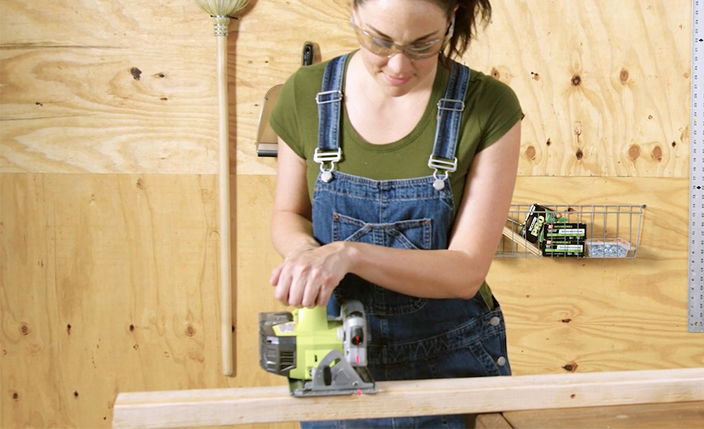 A worker trims studs for the DIY dog house.