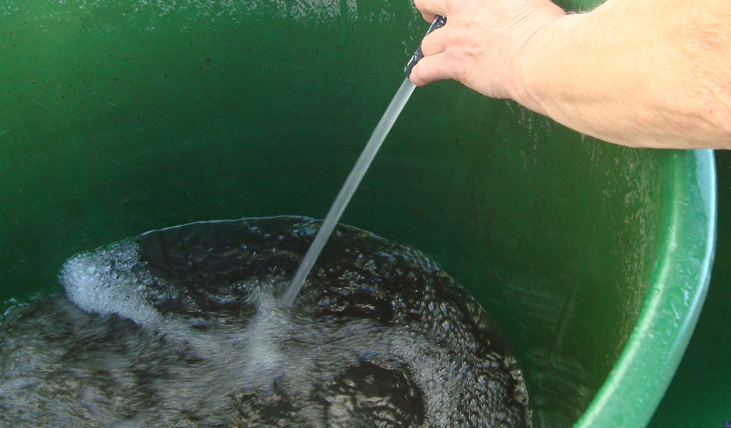 A person fills a bucket with water.