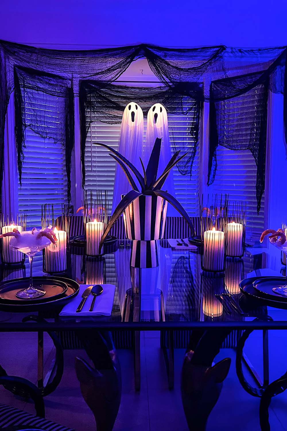 Dining room set up with Halloween decorations in blue lighting.