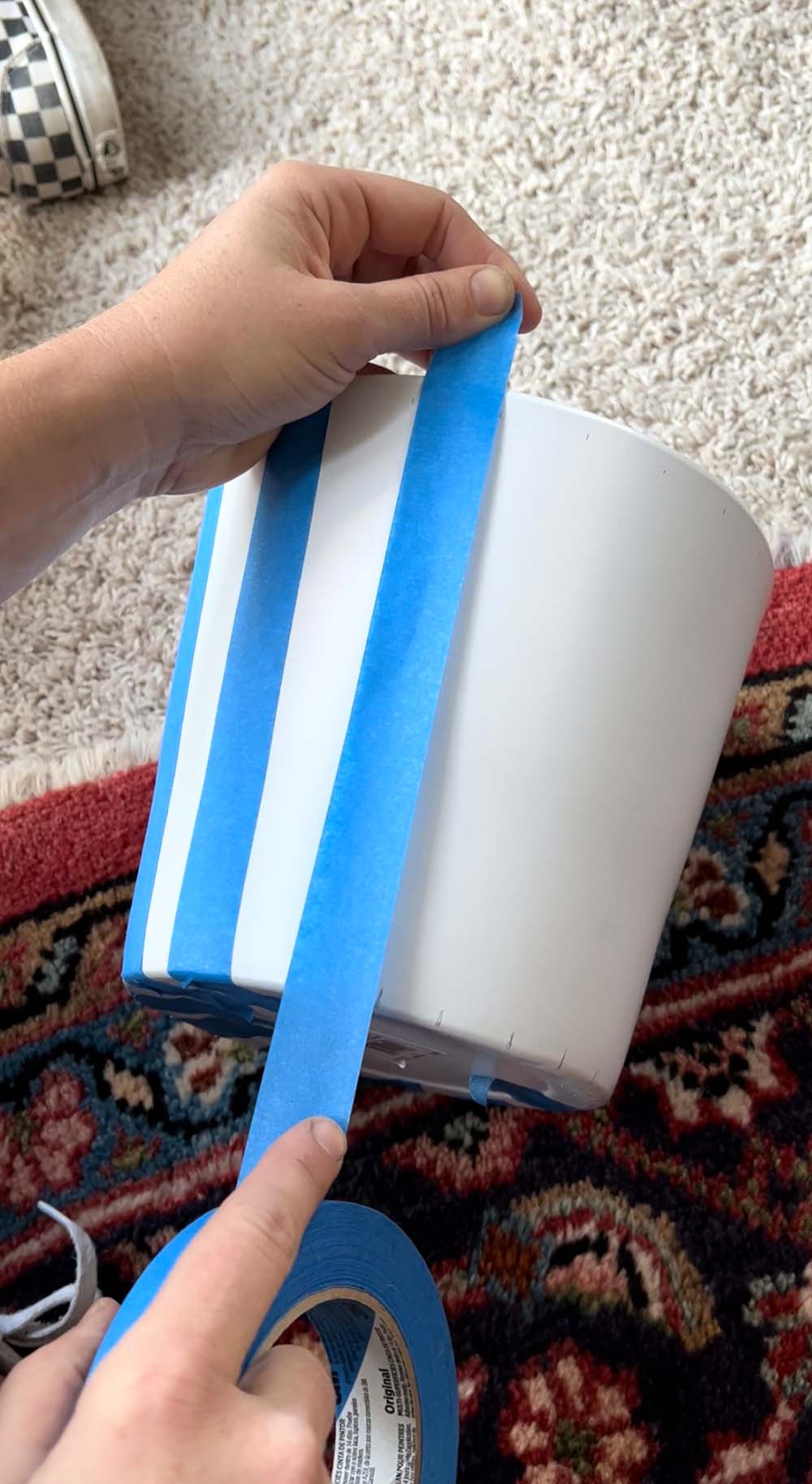 A white planter pot with tape lined upon it.