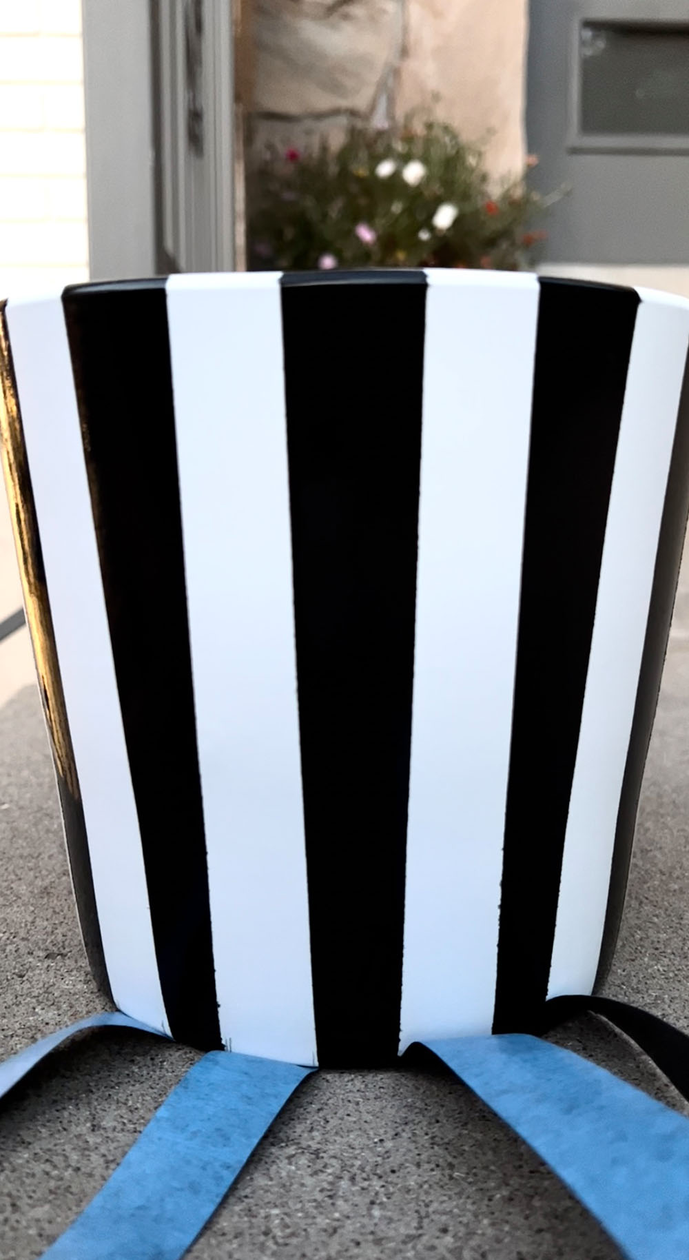 A white planter pot painted with black stripes.