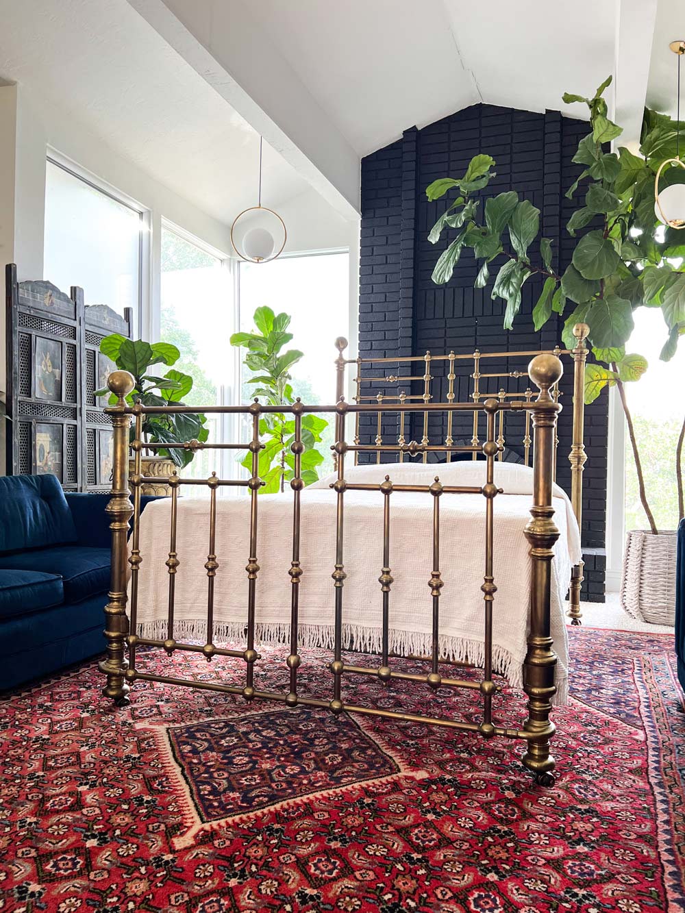 A room with a bed frame and red rug.