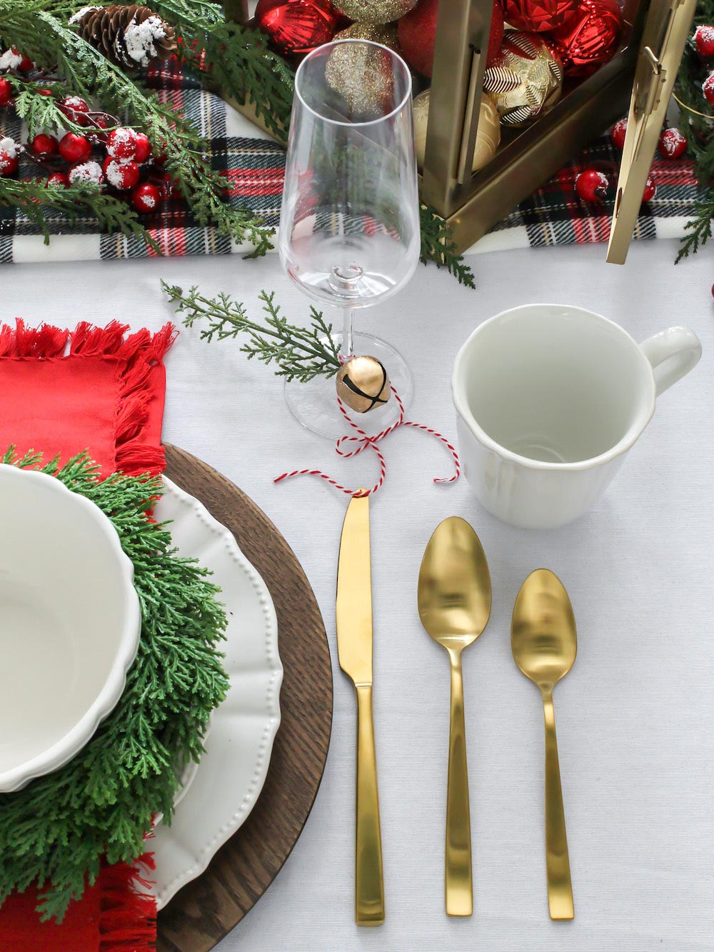 Ariel shot of decorated table containing gold cutlery, a wine glass, a coffee mug and holiday themed plates and bowls