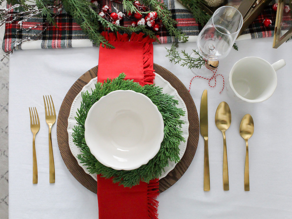 Ariel shot of dinner plate set up with gold cutlery and red and green decor surrounding it