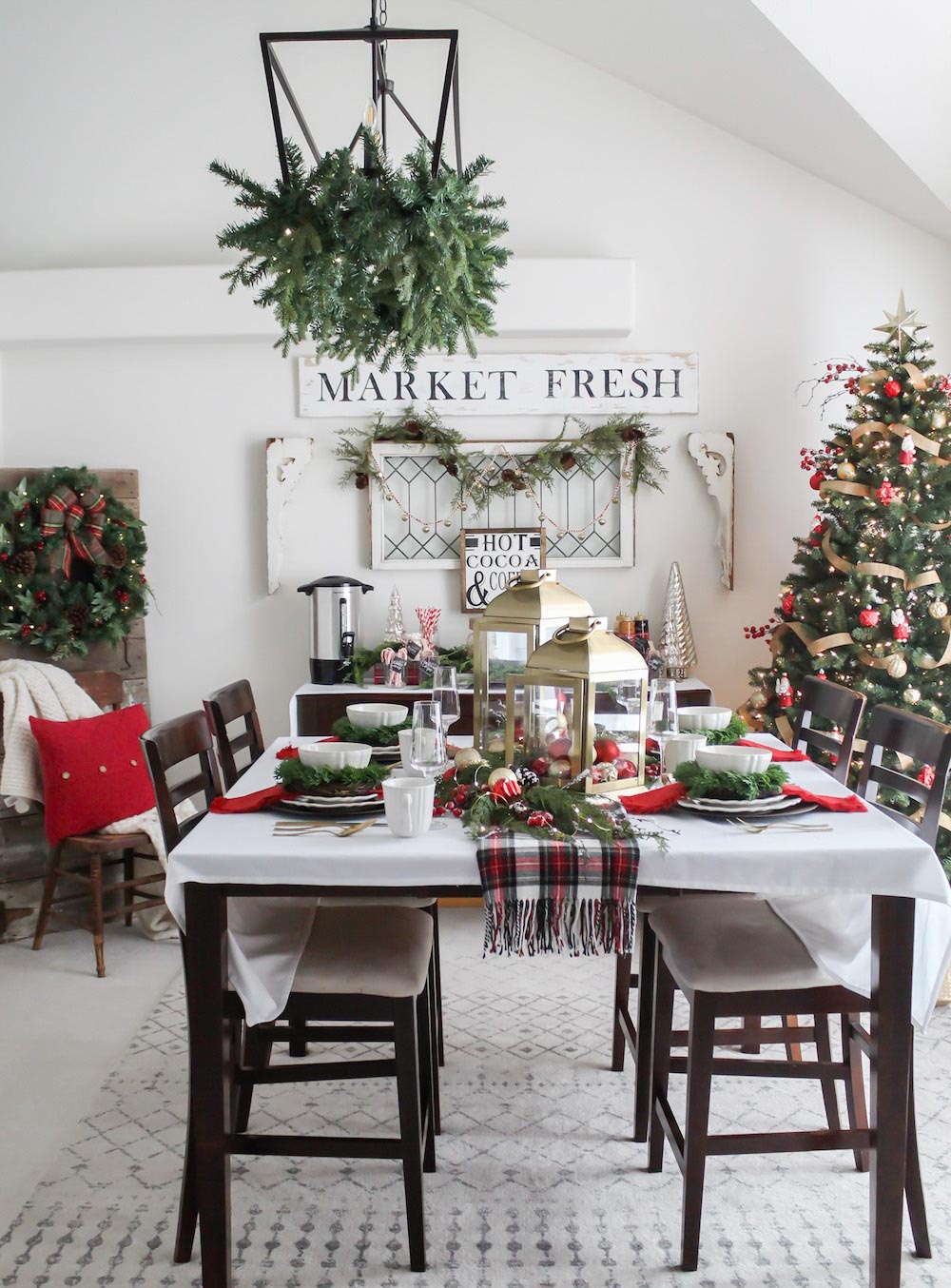 Holiday decorated Dining room containing a table with a with cloth, red, green and gold decor with a Christmas tree in the far right corner