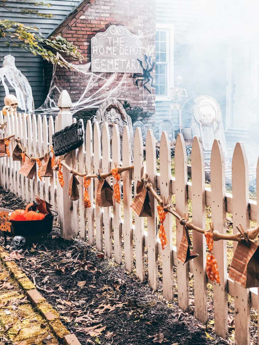 A fence decorated for Halloween with trick-or-treat bags.