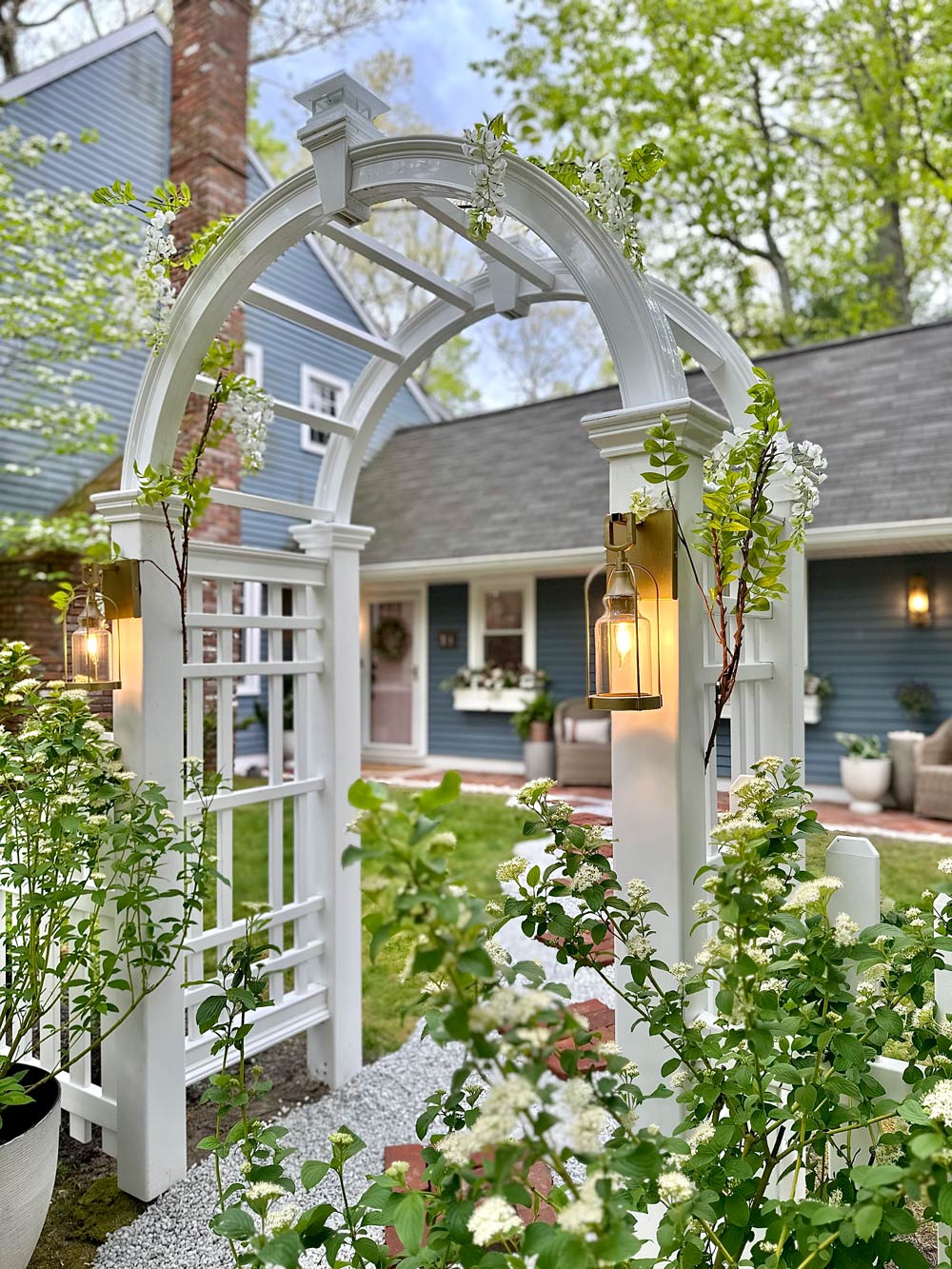White arbor archway into front yard with vining plants growing.  