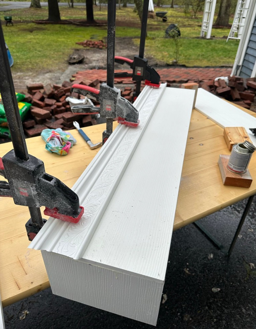 PVC trim being assembled on wood table outdoors. 