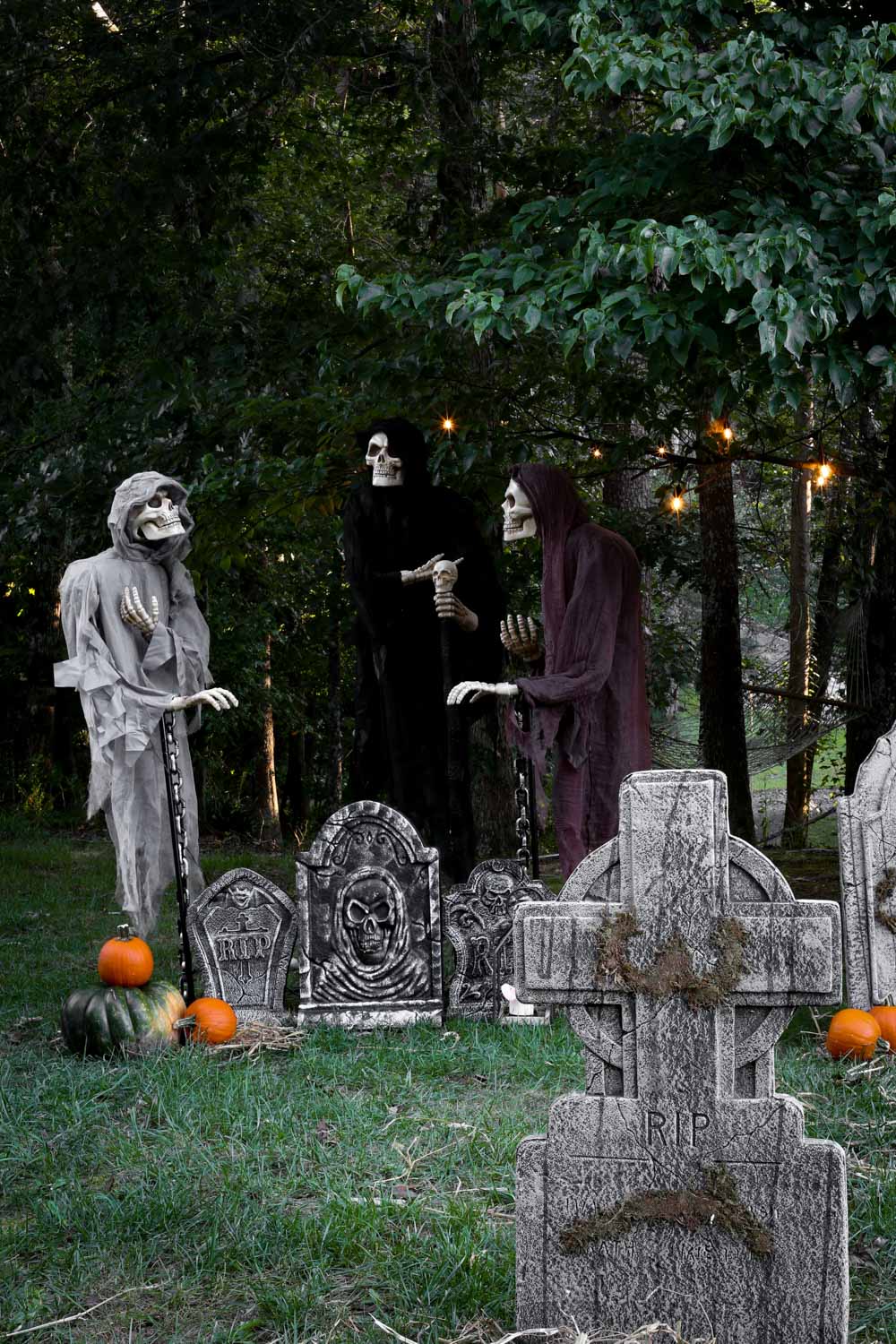 Three floating reapers float above tombstones in a haunted graveyard.