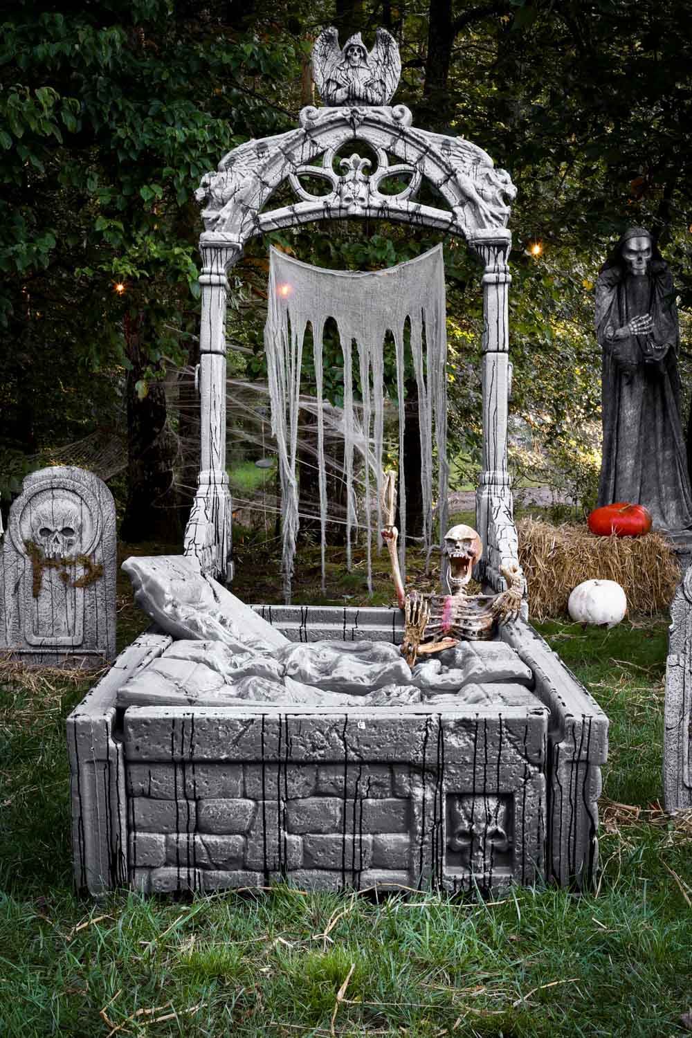 A skeleton bursting out of a crypt in a graveyard.