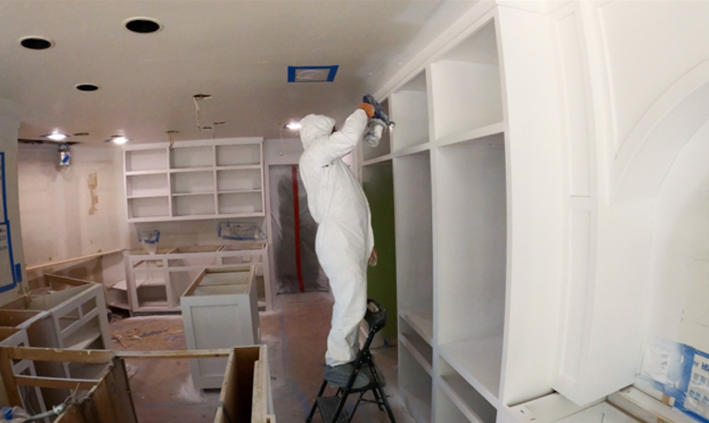 A person sanding kitchen cabinets.